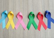 Different colored cancer ribbons on a gray wood background